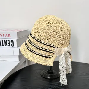 Beige woven straw bucket hat with black stripes and a large white lace flower bow decoration