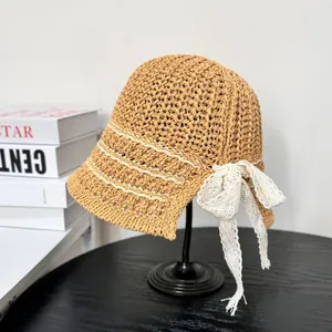 Summer straw bucket hat with white lace bow and stripes on a minimal display stand