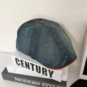 Detailed top view of retro denim ivy cap with orange stitching on decorative books