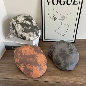 Tre cappelli newsboy tie-dye grigi, arancioni e antracite su uno sfondo vintage retrò