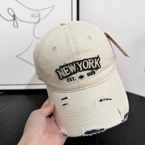 Detail of distressed beige denim baseball cap with New York Est. 1989 embroidery