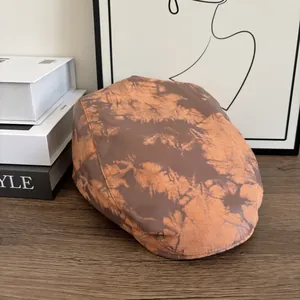 Dettaglio del berretto newsboy vintage tie-dye marrone su un tavolo di legno