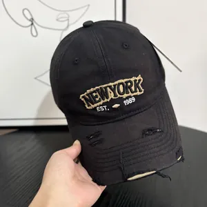 Close-up of distressed denim baseball cap with yellow New York 3D embroidery and rips