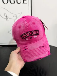 Detail of rose red distressed denim baseball cap featuring New York embroidery and vintage holes