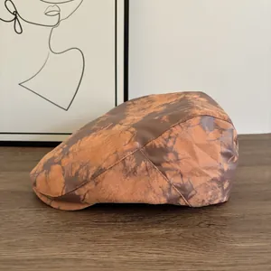 Dettaglio di un berretto piatto vintage con trama tie-dye marrone e arancione su legno