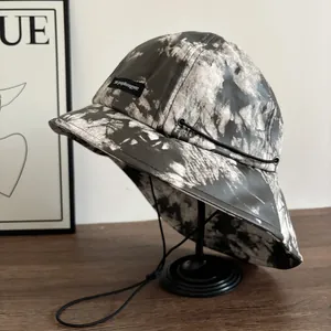 Cappello alla pescatora tie-dye bianco e nero con cordino regolabile su supporto essenziale