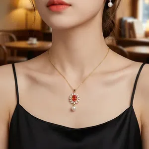 Elegant gold flower necklace with orange gemstone and pearl pendant shown on model