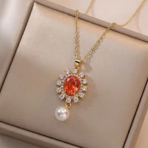 Elegant gold necklace featuring orange sunburst pendant with diamonds and pearl droplet