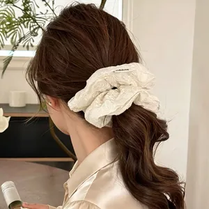 Beige floral embroidered oversized scrunchie on ponytail for elegant hair styling
