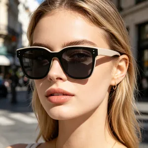 Gros plan de lunettes de soleil carrées élégantes noires et crème portées en extérieur