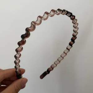 Detail of slim wavy brown translucent resin headband with minimalist hair accessory design
