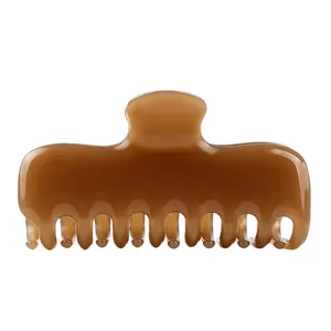 Detalle de pinza para el pelo de acetato de celulosa ámbar oscuro con acabado brillante