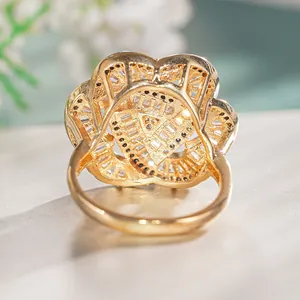 Detail of gold floral ring featuring hollow design with white baguette and black zircons