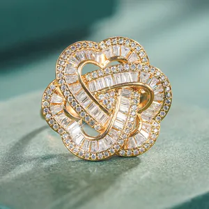 Elegant gold-tone heart flower ring with sparkling cubic zirconia on green background