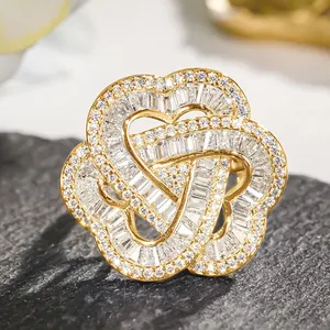 Macro detail of a gold flower ring featuring three heart-shaped petals with pavé zircons