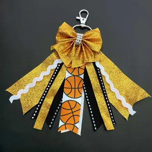 Detail of glitter gold bow keychain with basketball pattern ribbons and metal clasp
