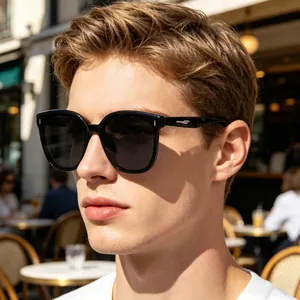 Close-up of a man wearing black square polarized sunglasses in a sunny outdoor cafe setting