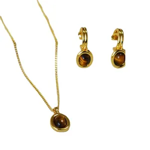 Vintage gold necklace and tiger eye earrings set with oval brown gemstones on white background