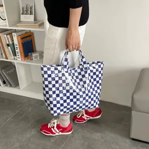 Detail view of a blue and white checkered waterproof PVC tote bag with stylish top handles