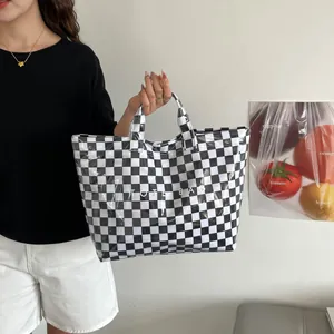 Detailed view of checkered tote bag with white TOTE BAG lettering and glossy PVC finish