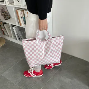 Pink and white checkered PVC tote bag with TOTE BAG text print in a lifestyle setting