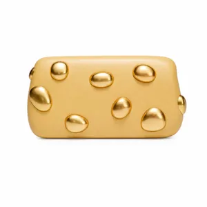 Close-up of warm yellow leather clutch with artistic gold irregular metal hardware