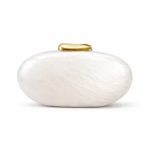 Detail of white pearlescent evening clutch featuring a golden irregular metal clasp