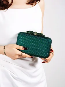 Detailed view of dark green rhinestone evening clutch with crystal bow clasp and chain
