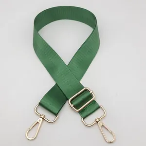 Detail view of emerald green adjustable nylon bag strap with gold metal lobster clasps