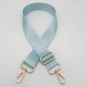 Detail of light blue adjustable nylon strap with gold metal lobster clasps and twill texture