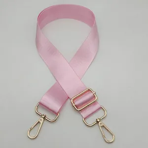 Detail of light pink nylon bag strap with polished gold-tone metal lobster clasps