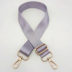 Detail of adjustable purple nylon bag strap with gold metal lobster clasps and buckle