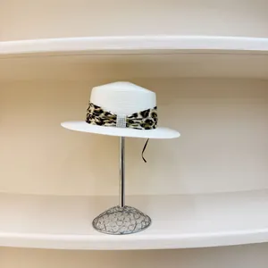 Flat top straw sun hat with leopard ribbon and pearl buckle on a display stand