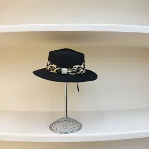 Detail of black straw hat featuring leopard print ribbon and pearl embellishment