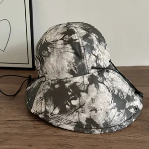 Dettaglio cappello da sole tie-dye con tesa larga, cordoncino regolabile e occhiello in metallo