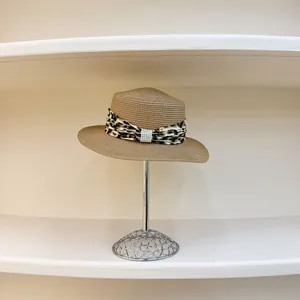Detailed macro view of straw hat with leopard print ribbon and elegant pearl buckle