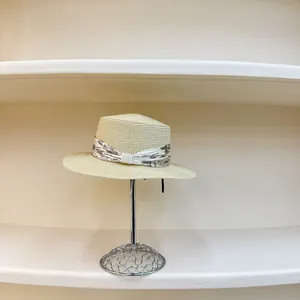 Close-up of beige straw boater hat with floral ribbon and triple-row pearl detail