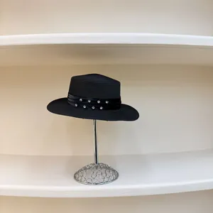Detalle de sombrero de paja con cinta negra decorada con filas de pedrería brillante