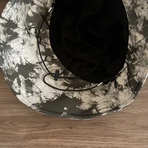 Dettaglio della fodera in rete nera e del cordino antivento del cappello alla pescatora tie-dye
