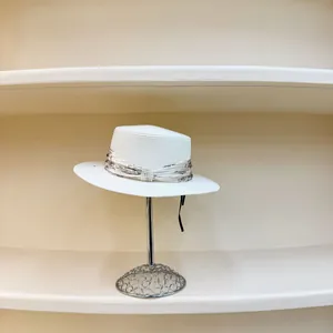 Detail of white straw hat with printed ribbon, pearl beads and elegant black ties