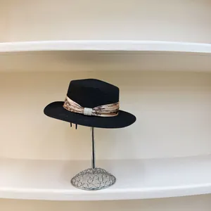 Detail of black straw boater hat with floral ribbon and elegant pearl buckle accent