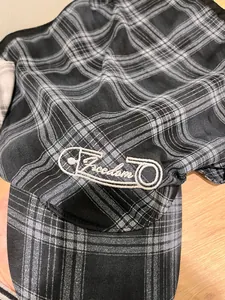 Close-up of Freedom embroidery with safety pin design on checkered newsboy cap fabric