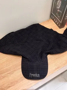 Close-up of black checkered sun hat with Freedom embroidery on a wooden surface