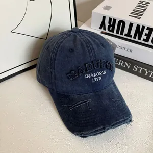 Close-up of distressed denim baseball cap with 3D embroidery and vintage worn brim