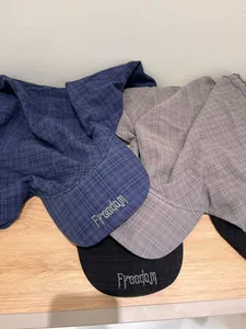 Close-up of three checkered sun hats with Freedom embroidery in blue, gray and black