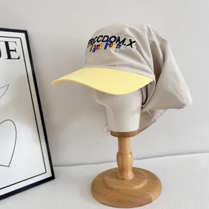Detail view of beige soft top cap with yellow brim and neck protection sun flap