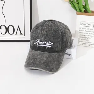 Détail de la broderie blanche Australia sur une casquette en jean gris foncé délavé