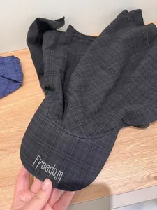 Close-up of grey plaid baseball cap featuring Freedom embroidery on the visor
