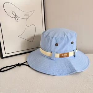 Close-up of sky blue sun hat with brown leather logo patch and metal ventilation eyelets