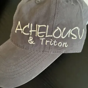 Close-up of white 3D embroidery on a dark grey distressed vintage cotton baseball cap